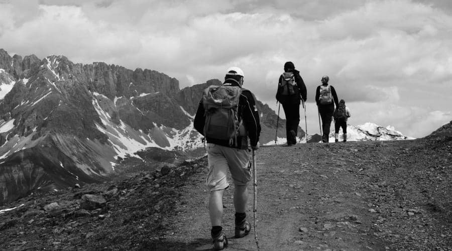 Randonneur équipé marchant sur un sentier de montagne dans les Pyrénées avec vue panoramique