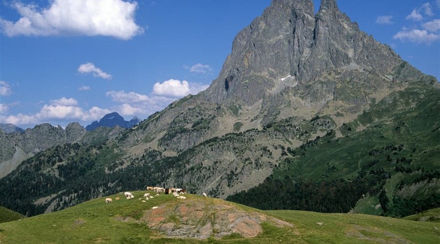 Randonneurs sur un sentier de montagne en vallée d'Ossau avec vue sur les sommets pyrénéens